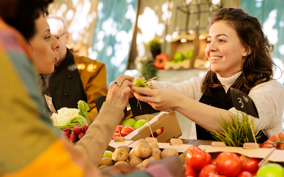 A woman stands behind a selection of produce