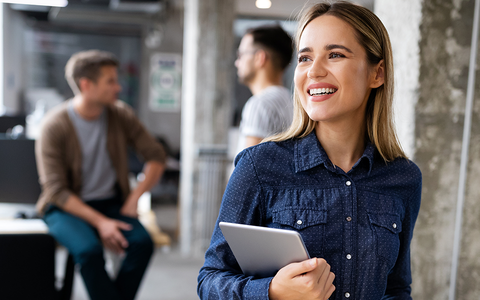 A woman is leaning thoughtfully against the wall, and she is holding her tablet