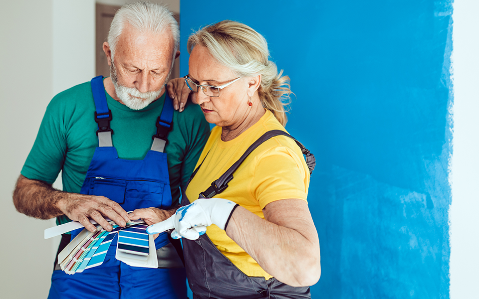 A man and woman look at color swatches to pick a paint color