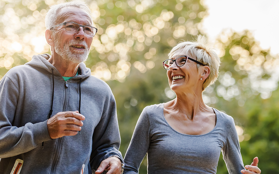 A man and woman are out, walking for exercise, and having a conversation