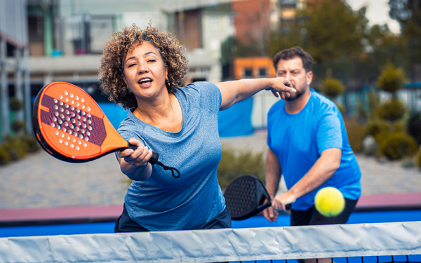 A couple are outside playing pickleball