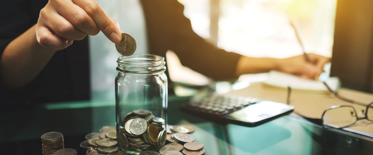 Business woman putting coins into a jar